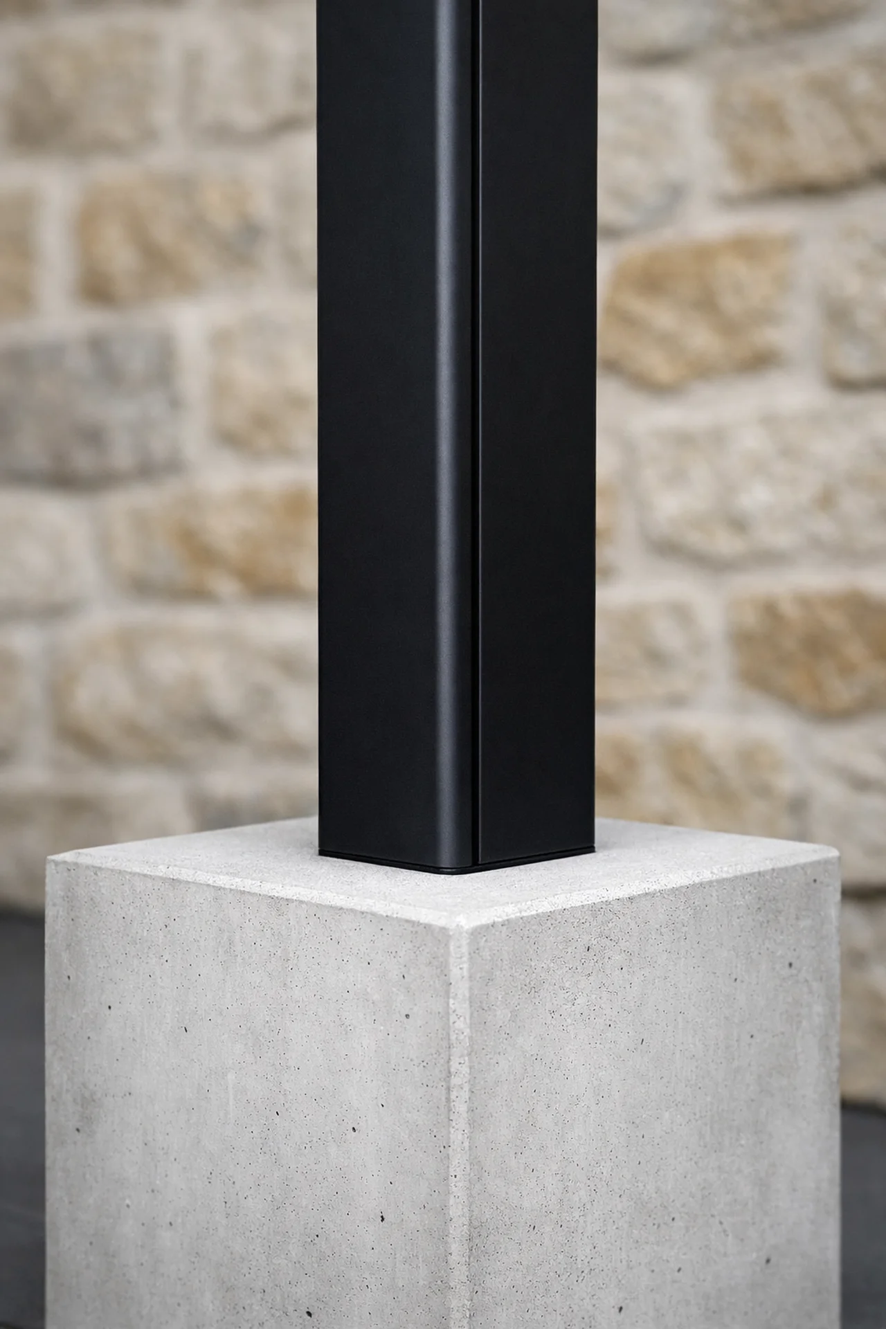 Detail einer modernen Pergola aus schwarzem Aluminium und Sichtbeton für minimalistisches Design.