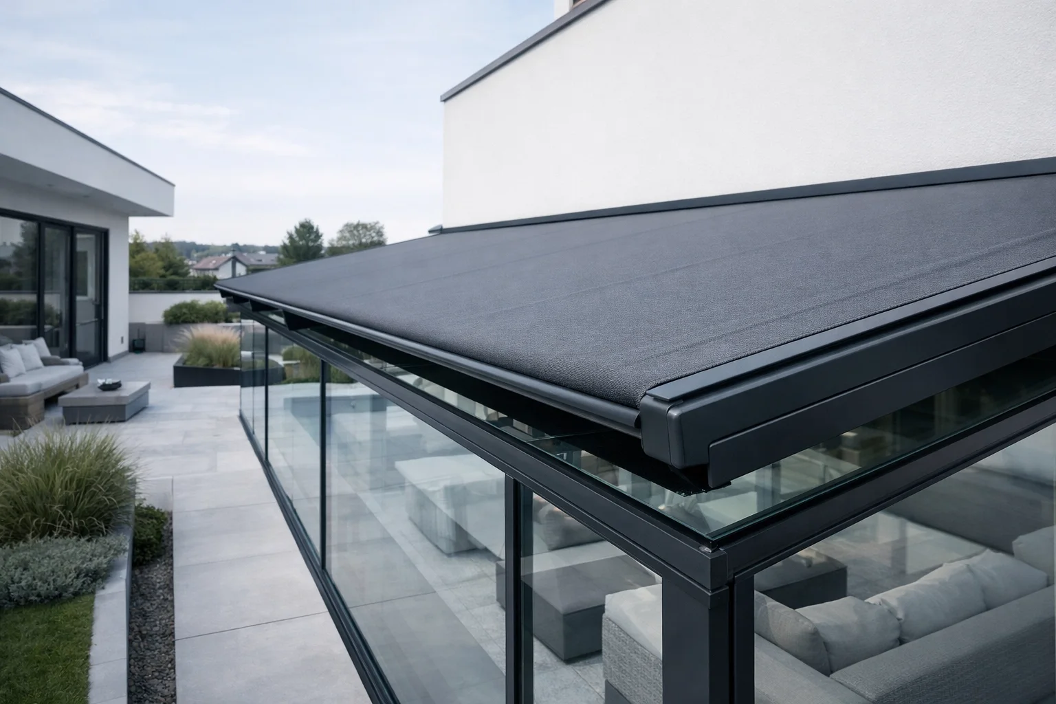 Anthrazitfarbene Aufglasmarkise nach Maß auf einer Terrassenüberdachung aus Glas.